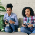 Two women playing video games on a couch.