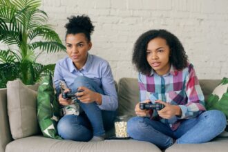 Two women playing video games on a couch.