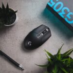 Close-up eines Logitech G502 HERO Gaming-Maus mit RGB-Beleuchtung, das auf einem Mauspad liegt, um das 25.600 DPI Sensor-Upgrade und die 11 programmierbaren Tasten zu zeigen.